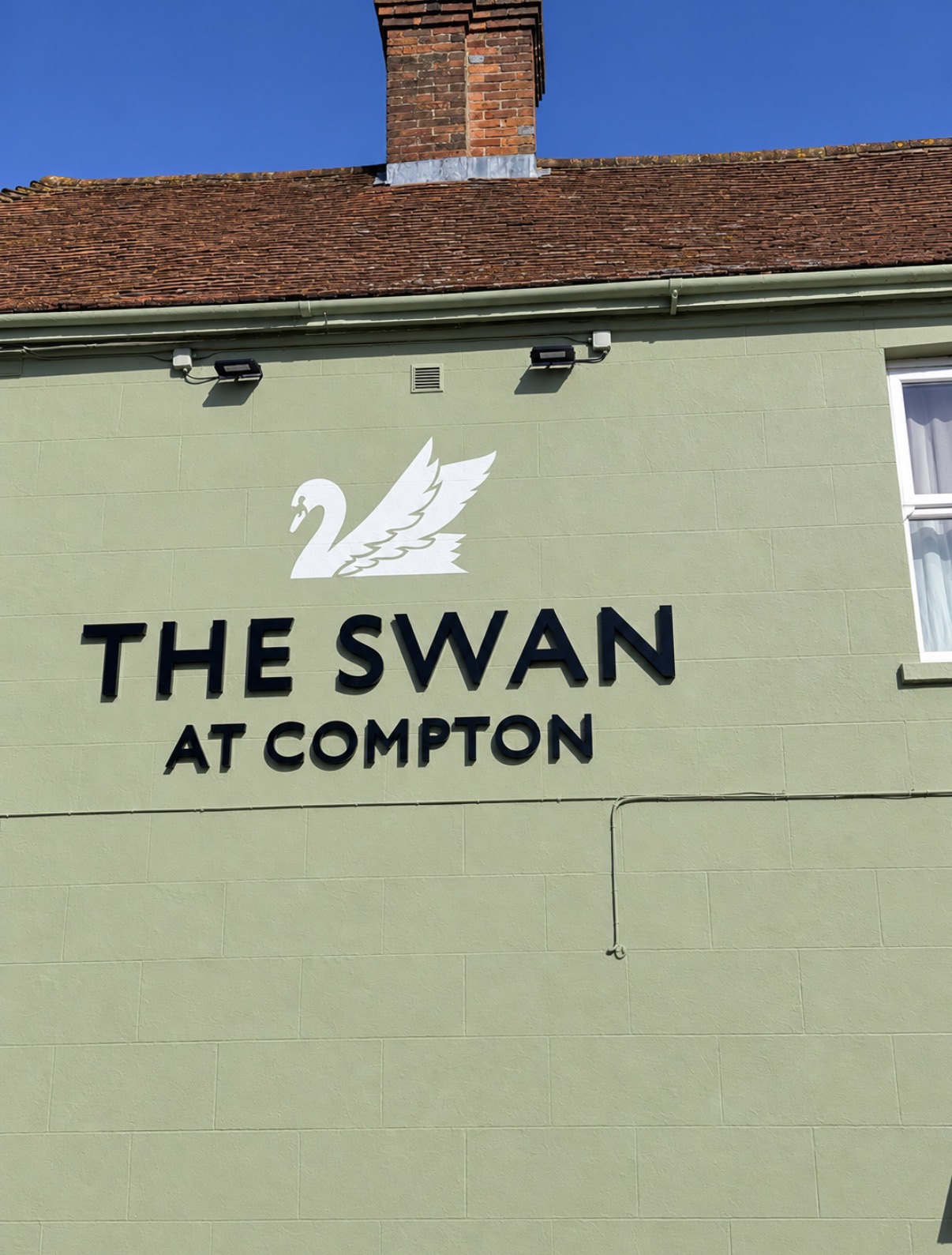 The Swan at Compton name and swan emblem on the pub exterior